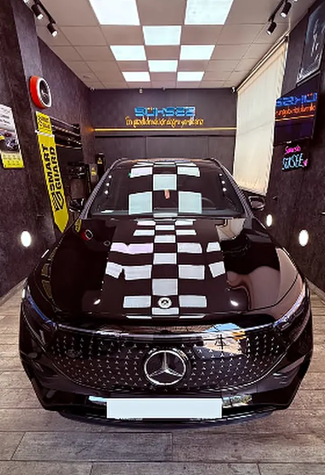 Süksee'de parlatılmış siyah Mercedes-Benz, tavandaki dama ışıklar kaputa yansıyor